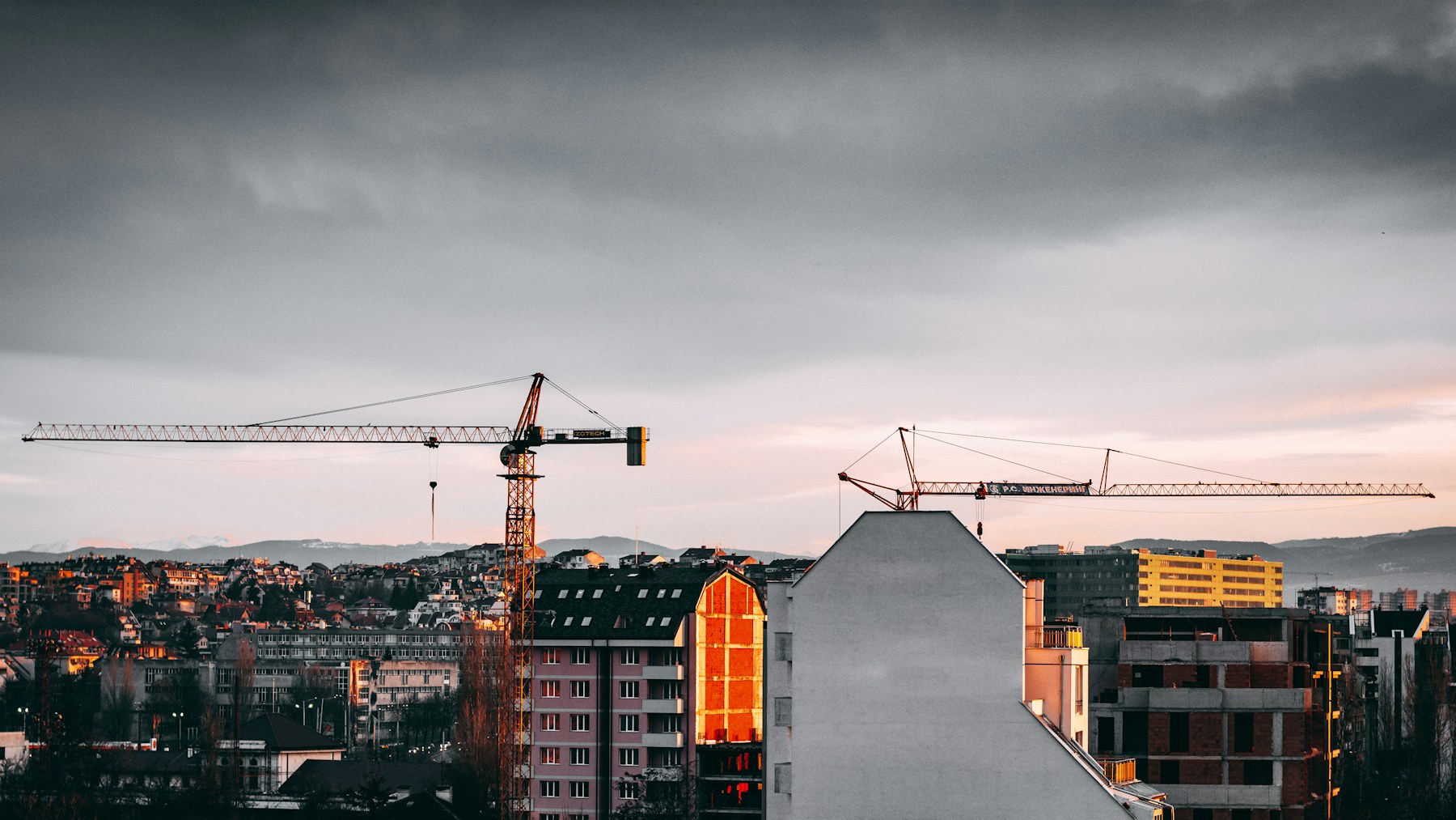 Residential construction site with apartment buildings, crane and architectural plans in a Bulgarian city setting.